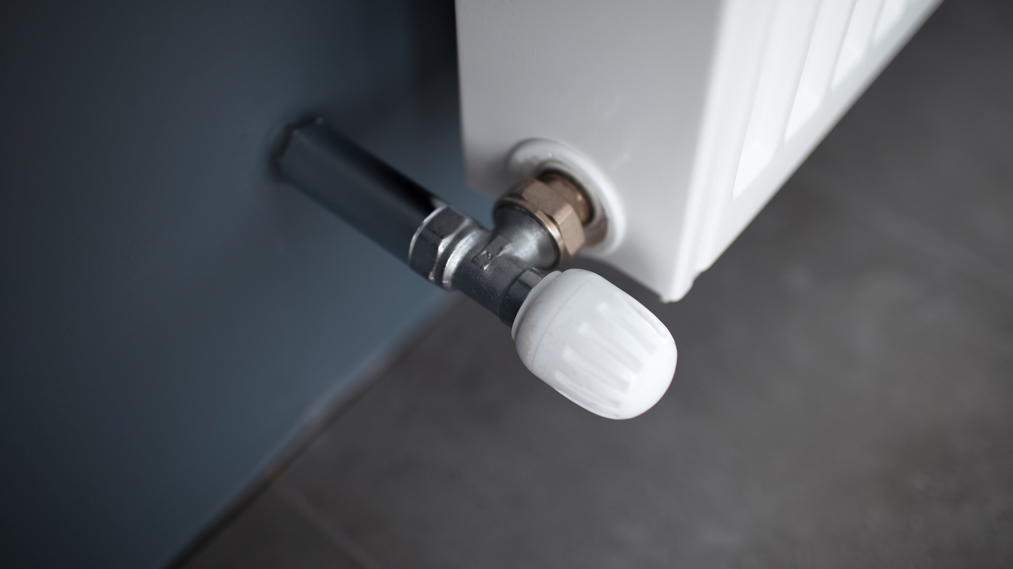 Close-up of a white manual control valve connected to a radiator.
