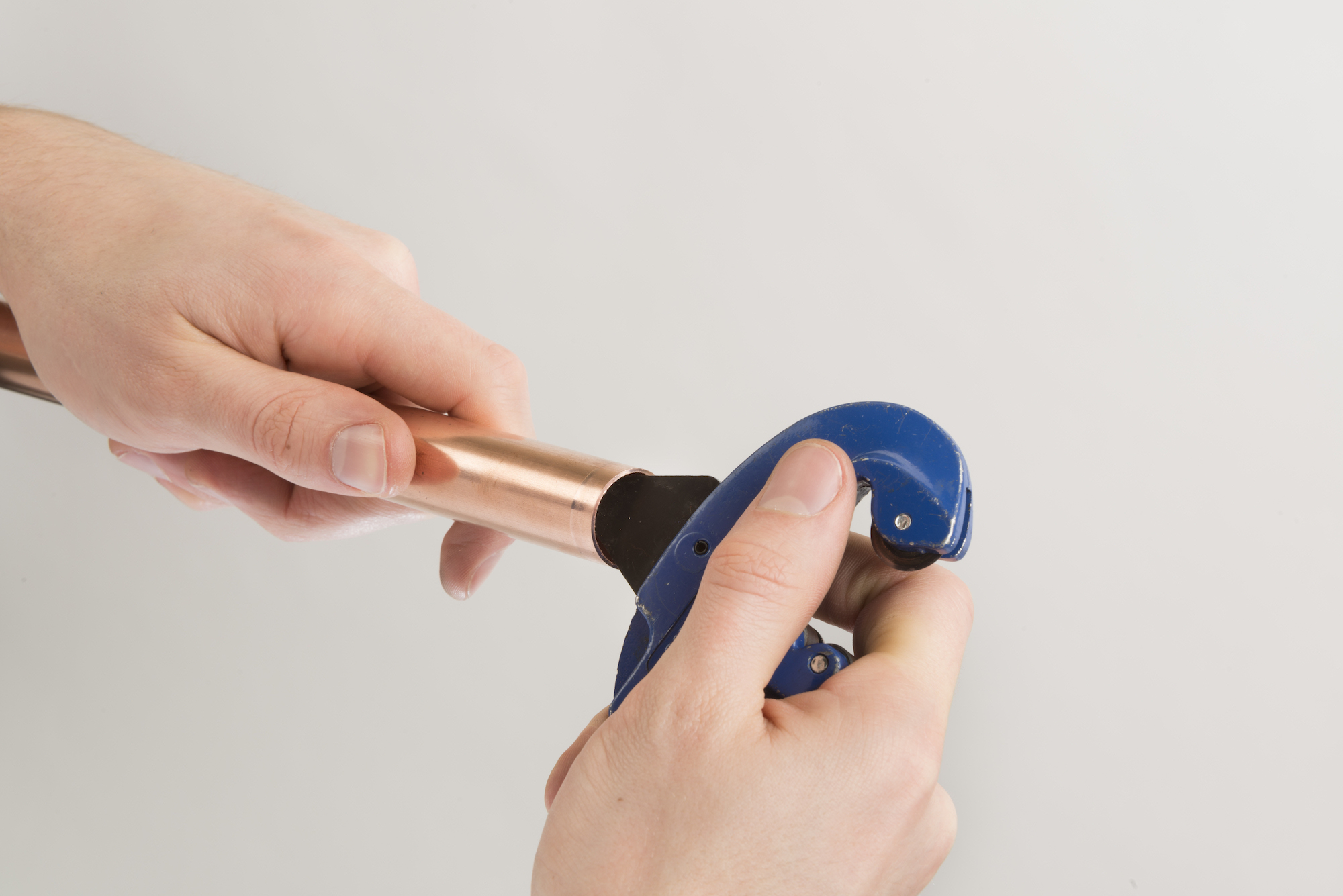 Hand using a pipe reamer to remove burrs from the end of a copper pipe.