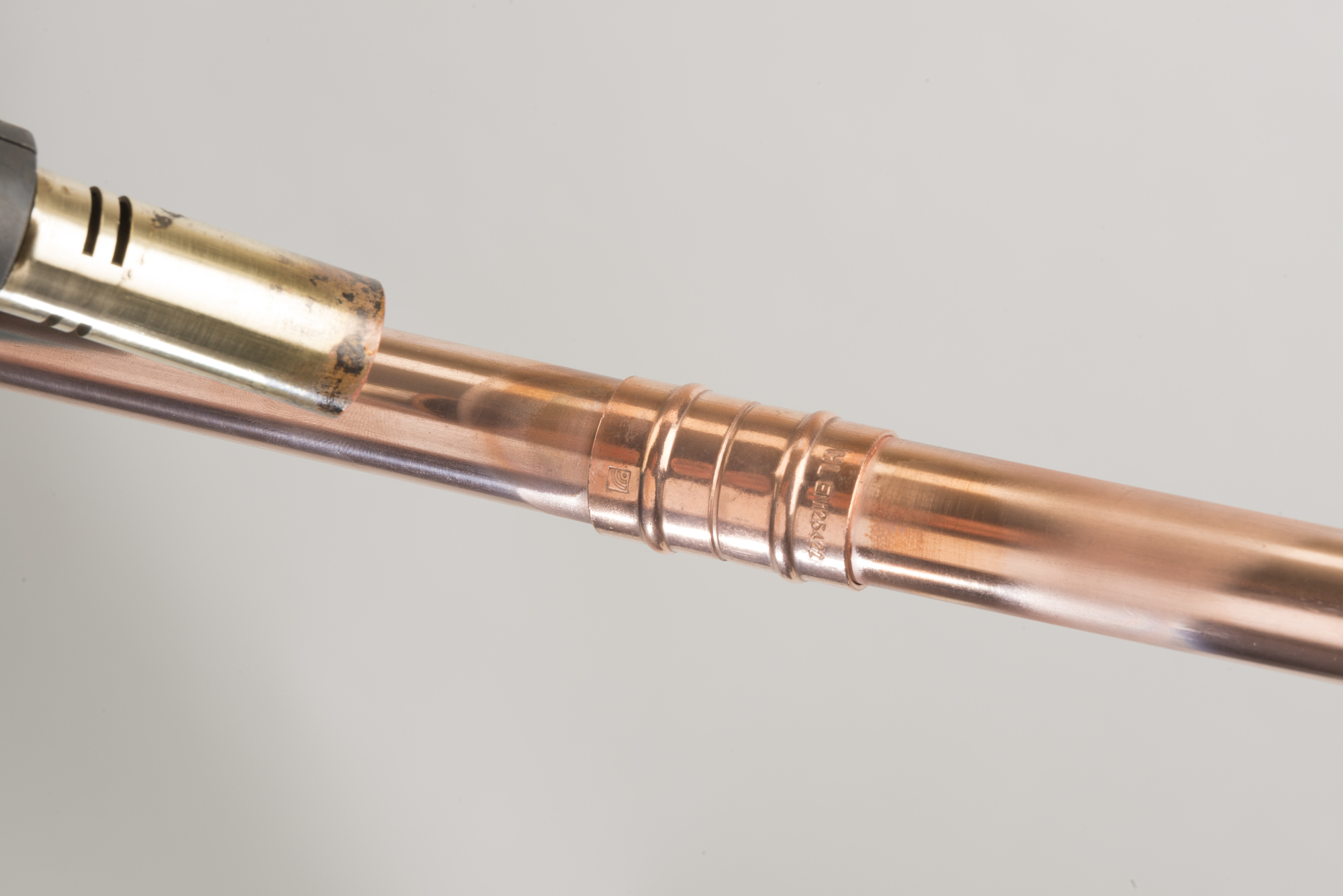 Blowtorch heating a solder-ring fitting that joins two copper pipes.
